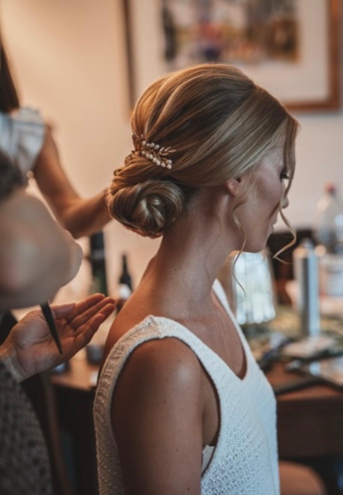 Haarschmuck wird in einen tief sitzenden Chignon gesteckt, Getting-Ready-Situation vor dem Spiegel